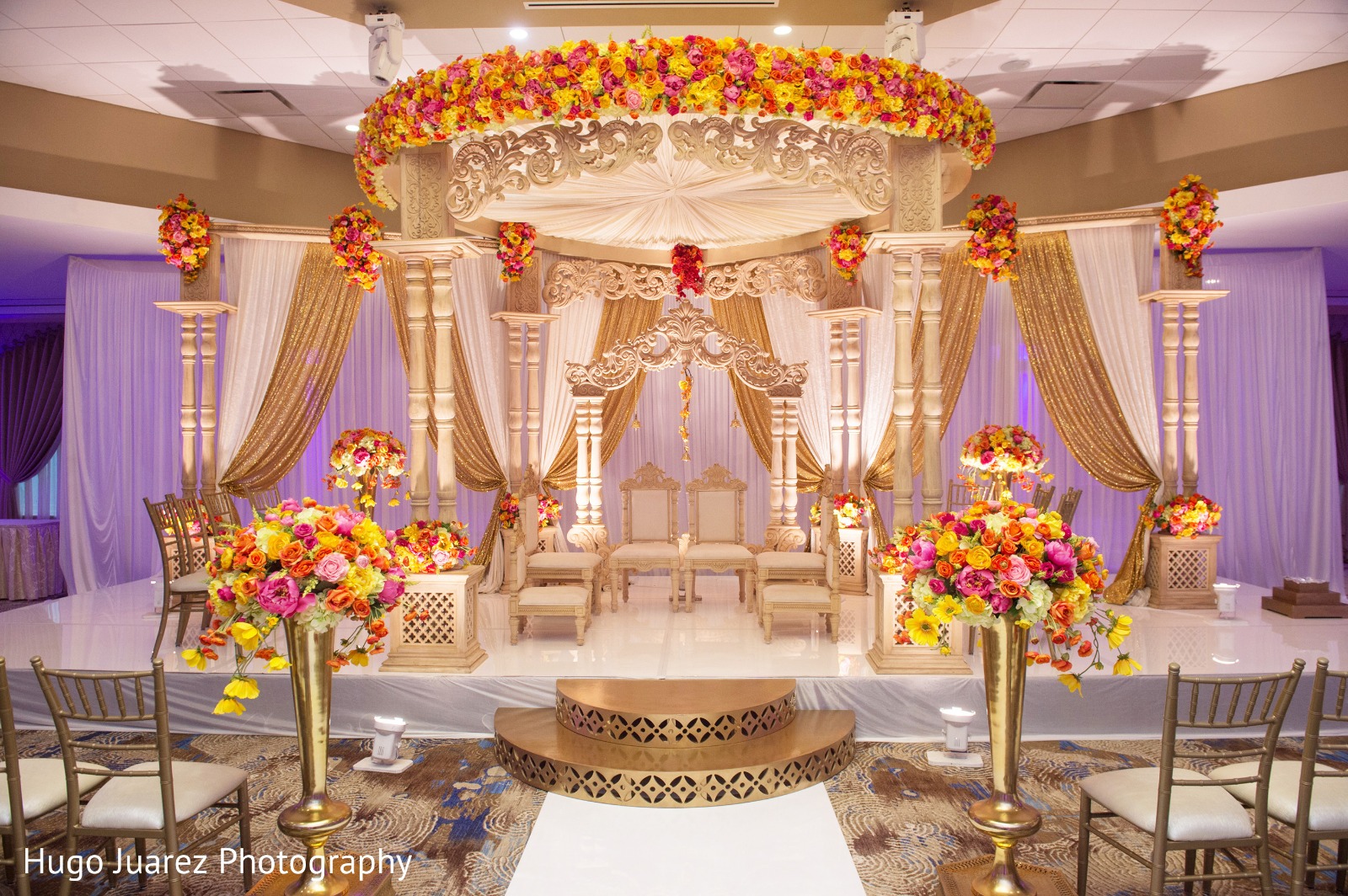 Purple and gold mandap with floral decorations